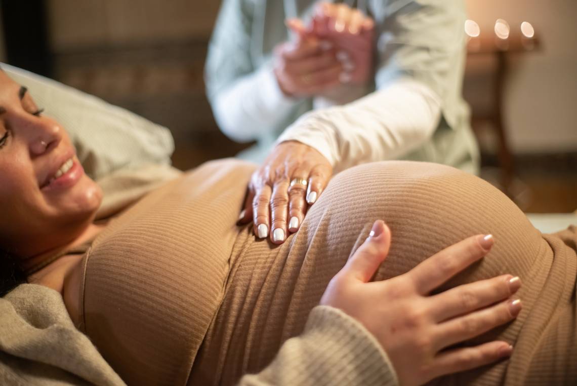Bild vom Bauch einer schwangeren, der von der Hand der Hebamme sanft berührt wird. Bild ist von Freepik