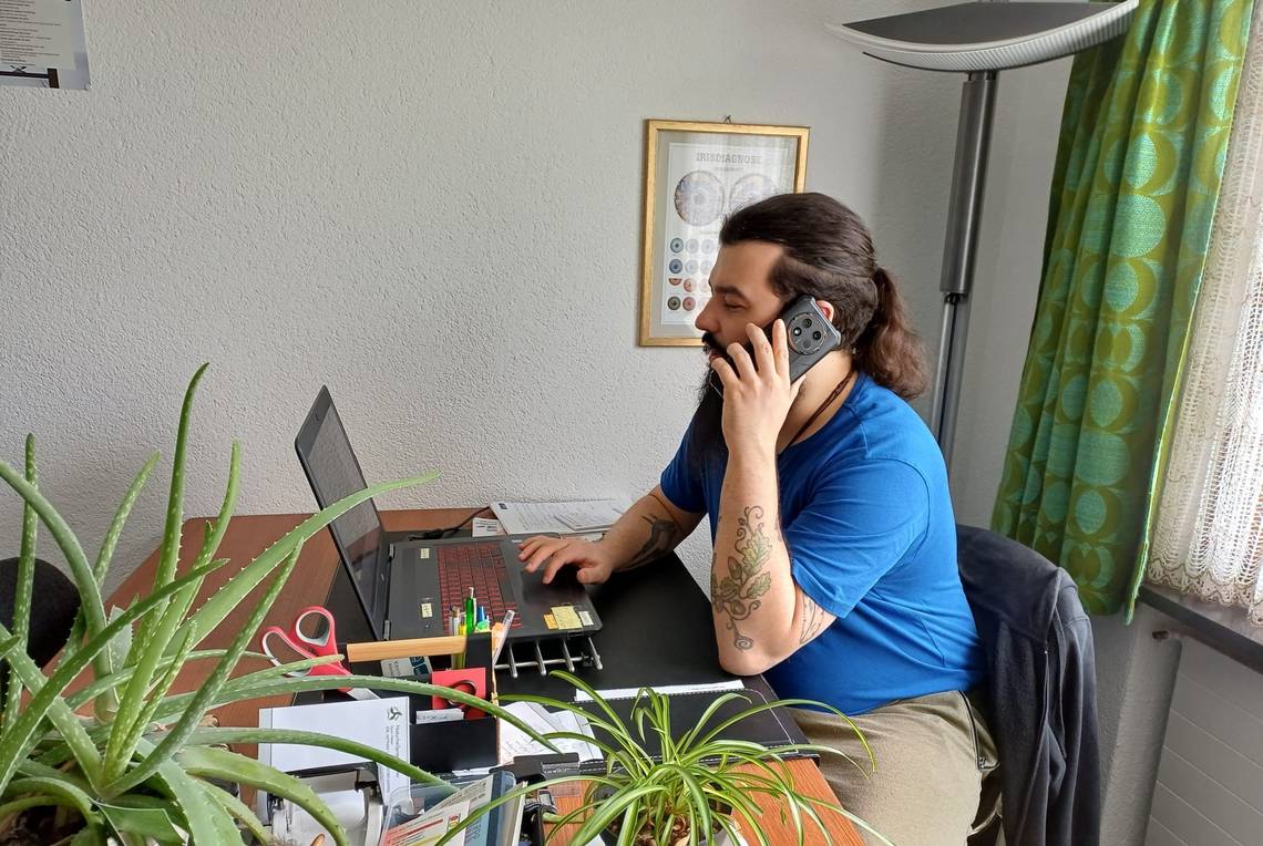 Kevin Meier sitzt an seinem Schreibtisch und telefoniert, er beantwortet die Interview-Fragen.