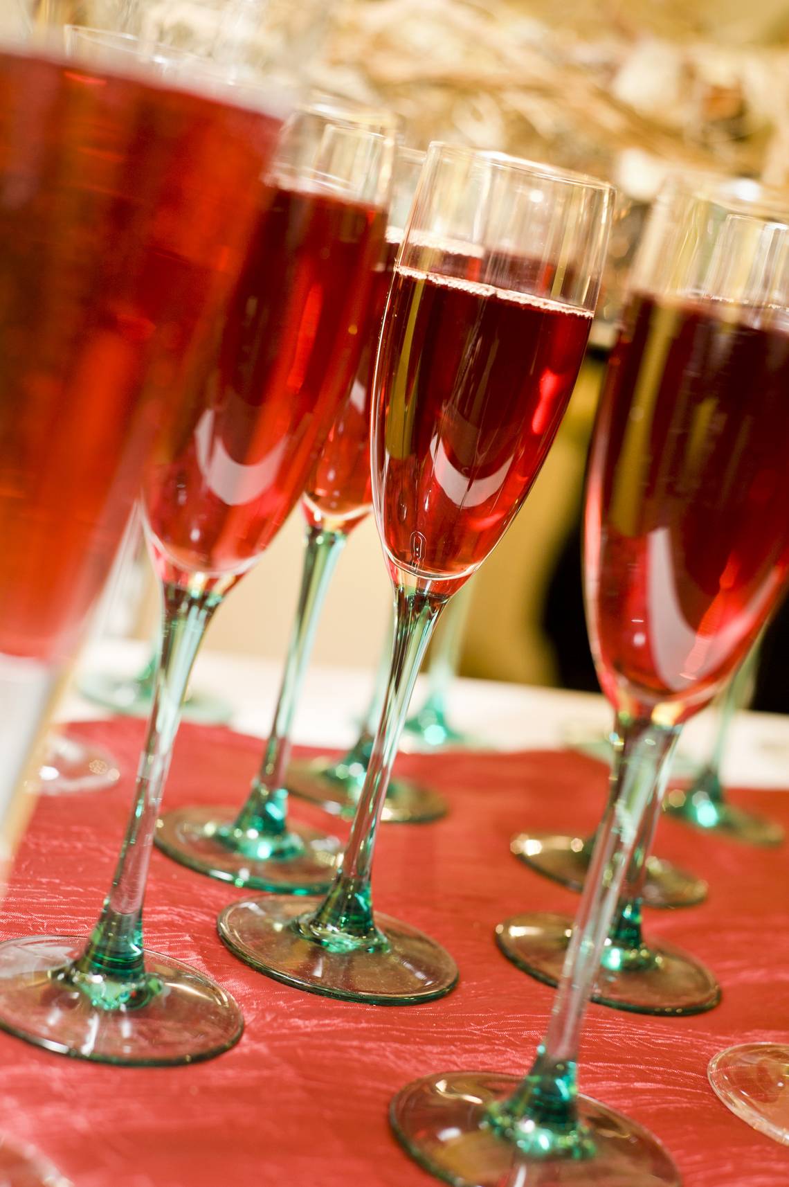 Mehrere Sektgläser mit rotem Getränk stehen auf einem Tisch.