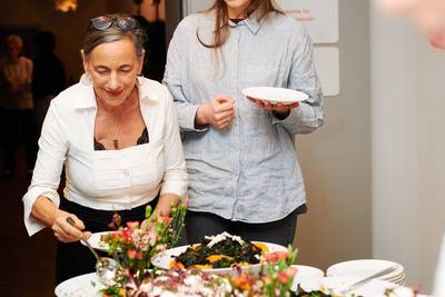 Zwei Personen vor einem Buffet mit verschiedenen Salaten und warmen Speisen in Schalen und Tellern.