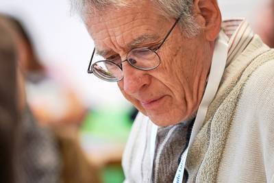Ein Mann mit Brille beugt sich über das Tagesprogramm und liest es aufmerksam.