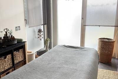 Behandlungsraum mit Massageliege, geflochtenem Wäschekorb und Regal mit Körben.